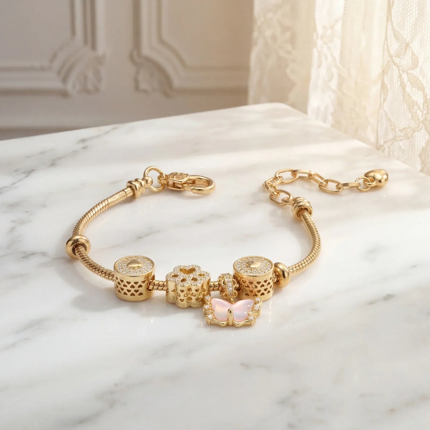 Gold charm bracelet with diamond accents and pink butterfly, displayed on marble surface