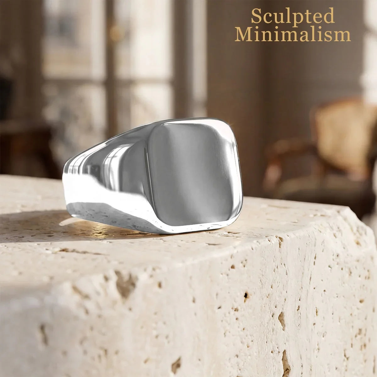 Minimalist silver signet ring displayed on stone surface in natural light