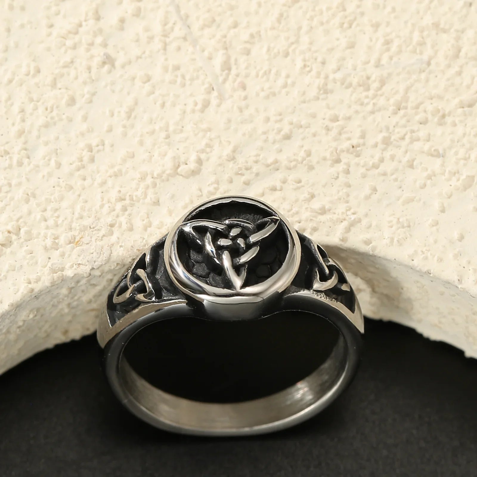Silver Celtic knot ring with black inlay on textured cream and black background