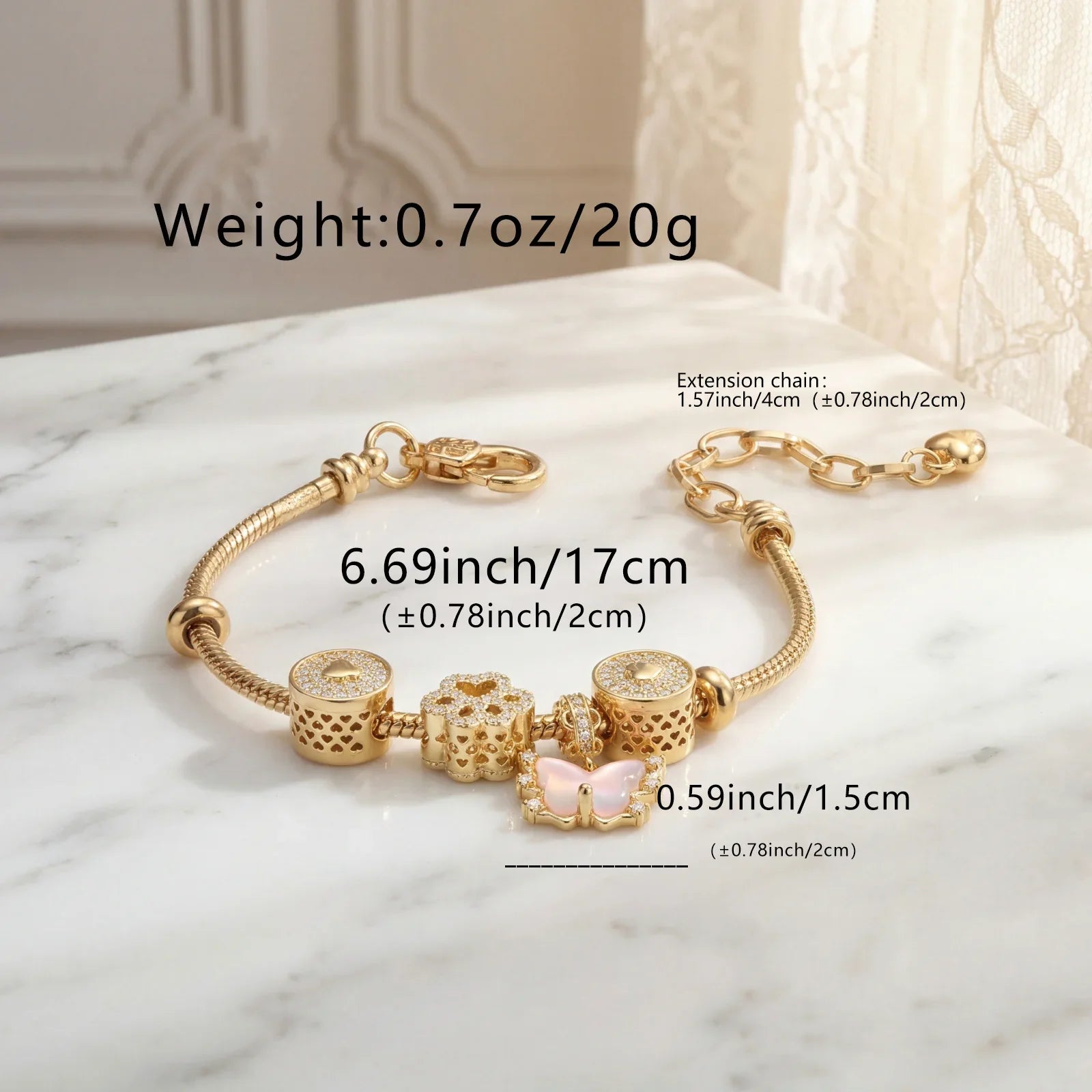 Gold charm bracelet with crystal accents and butterfly charm, displayed on marble surface with size details