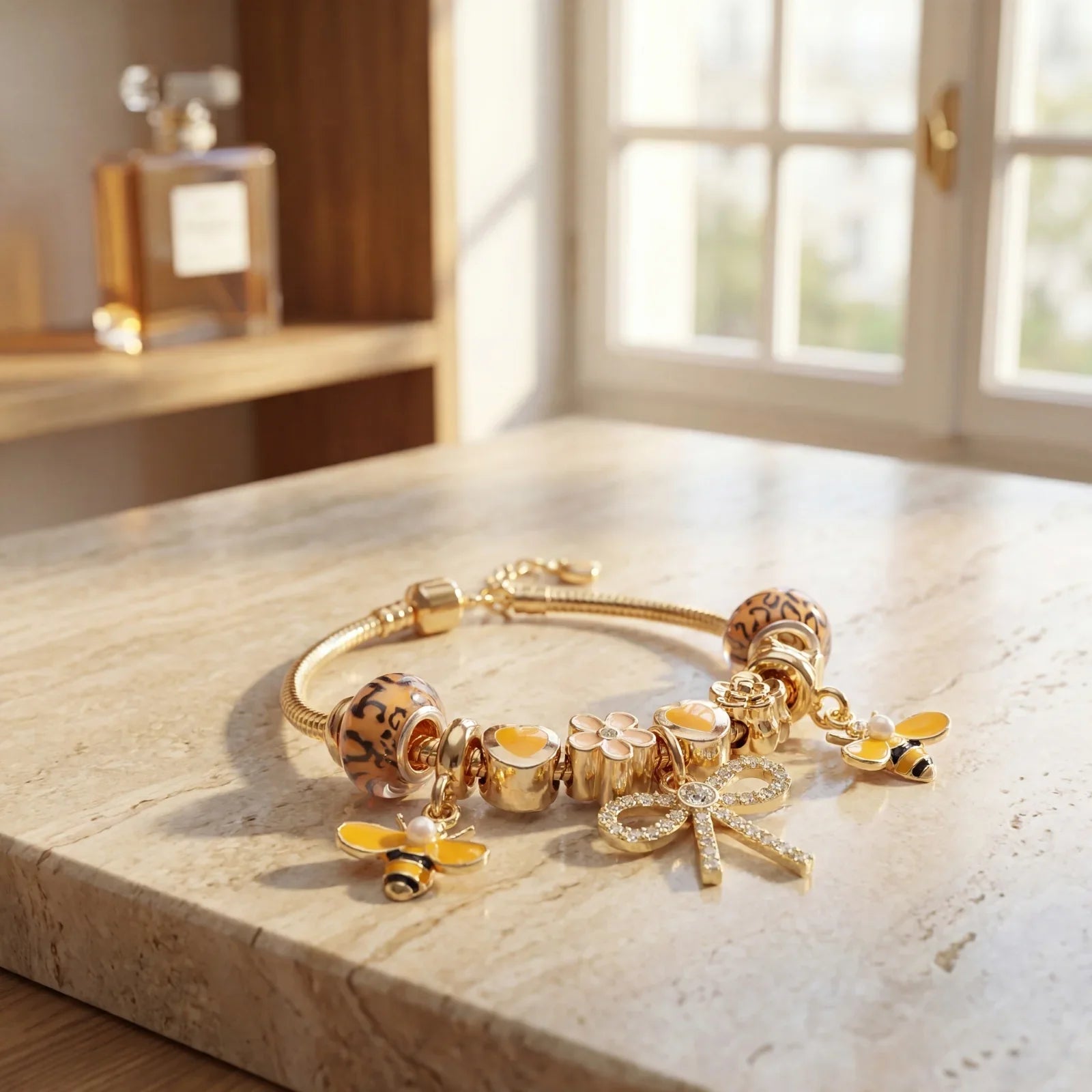 Gold charm bracelet with bee, flower, and bow charms on a marble surface in natural light