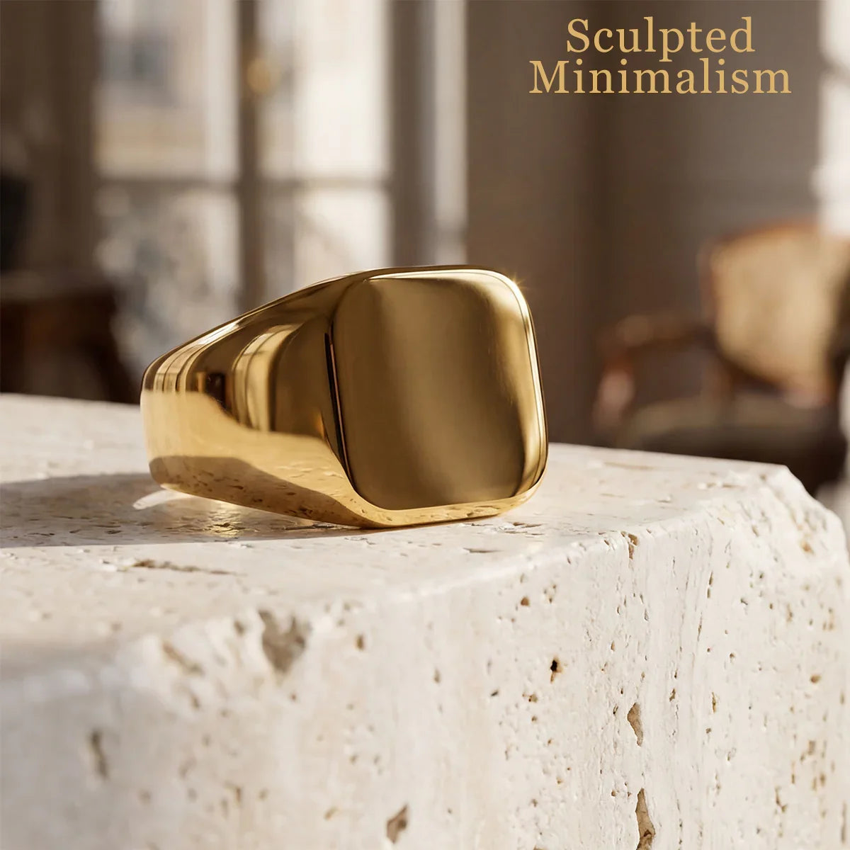 Minimalist gold signet ring with smooth, sculpted surface on beige stone background