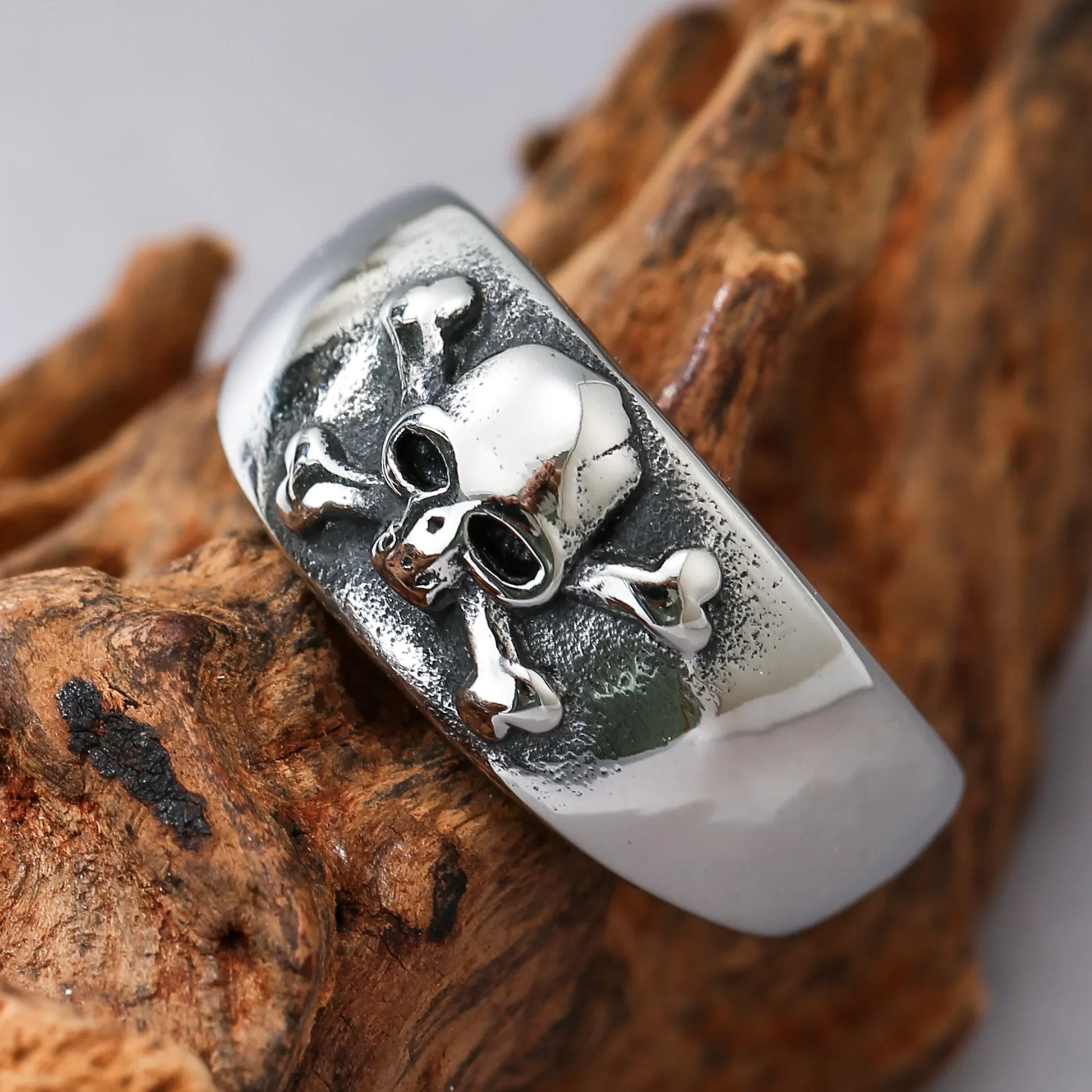 Men's silver skull and crossbones ring with textured band on wood background